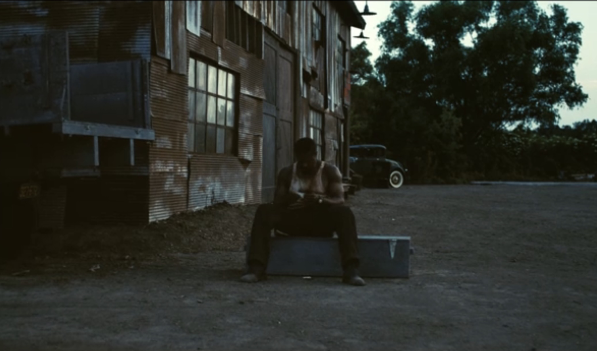 Smoke ends sitting alone, rusting away at sunrise in a tank top.